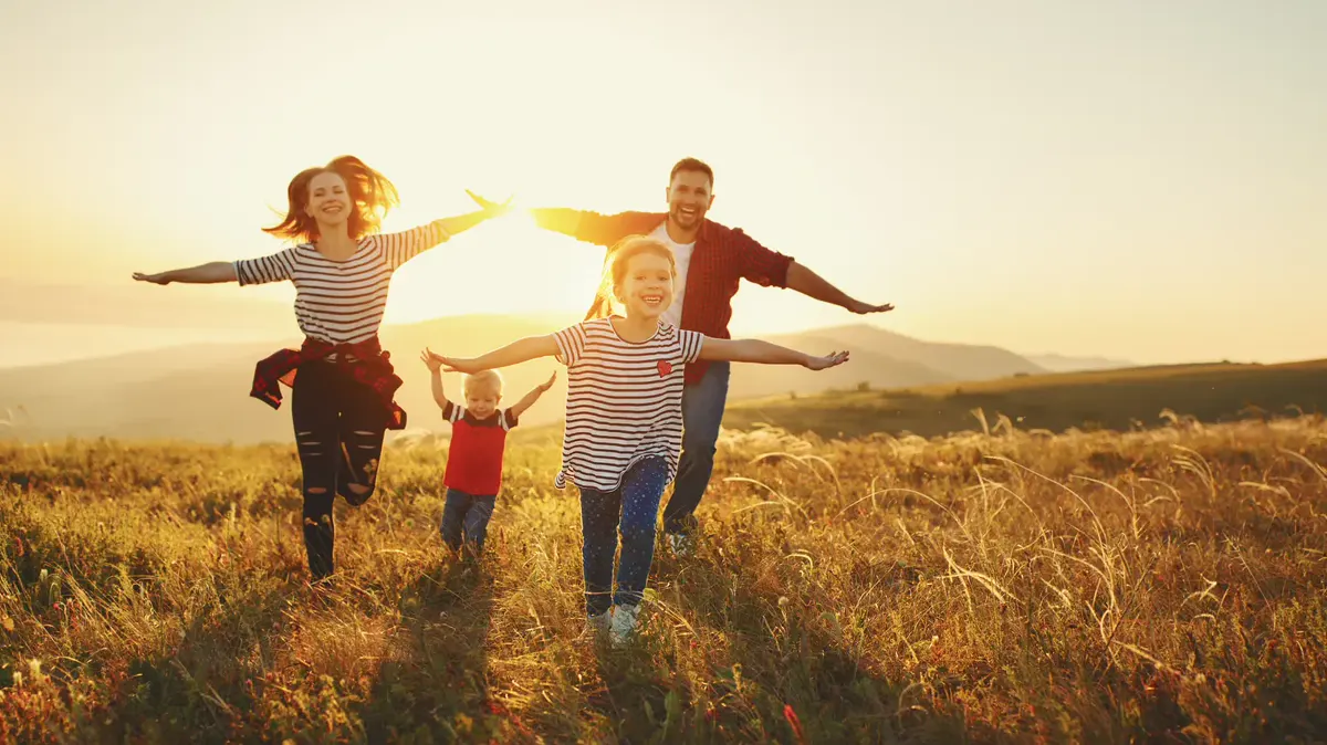 A family running through a golden field at sunset