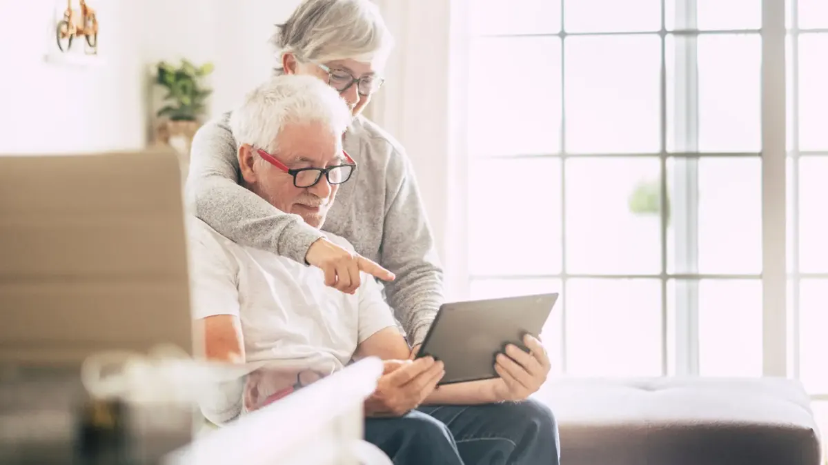 An older couple looking at a tablet together at home